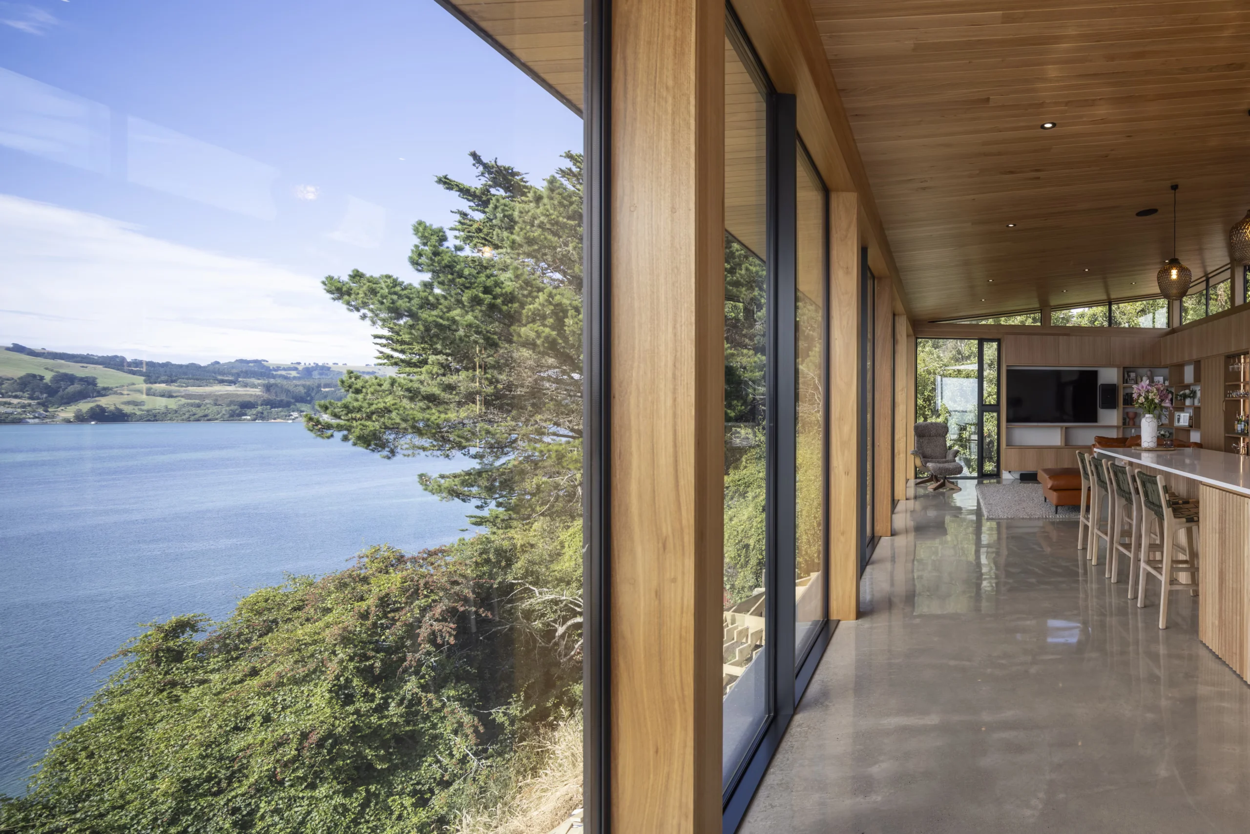 Timber-lined kitchen and living area with floor-to-ceiling windows overlooking the water at Meridian Street